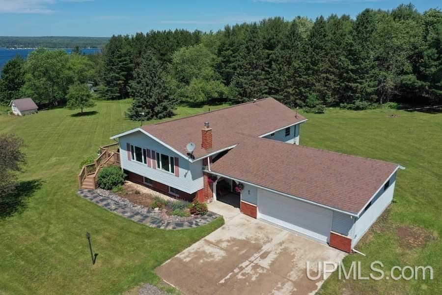 This fabulous home sits just outside the Village limits of beautiful L'Anse Michigan! It has nearly 2 acres and includes that million-dollar Lake Superior view that reveals itself from nearly every window in the home! The sellers have carefully remodeled this home to make its best features shine. The entry has been done in tile flooring and gives access to the attached garage as well as the large, manicured back yard. They've opened the kitchen, dining and living room area to natural scenery that this location has to offer and what no pictures can do justice!  New hardwood flooring throughout this main area, updated kitchen, and smart home features throughout. Gorgeous quartz countertops, timeless glass subway tile backsplash, and new soft close cabinets and drawers. The window above the deep sink brings in the expanded view of the lake and well cared for side yard. The dining area gives access through the new patio door to the deck! The hallway has the newly finished marble tile bathroom with ceramic backsplash, two bedrooms and the master bedroom with new bath. Again, you'll find beautiful marble and ceramic tile in this newly done space.  The lower-level finished basement area boasts a lot of space for family gatherings and company overflow. There's a nook that is the perfect office space, study area or for a craft/sewing table.  An additional bedroom is here, perfect for company and a full bath with shower and sauna! On the far end of the basement is a small workshop/utility room.  The lower level also features a nice laundry room with a HE w/d, a double wash tub sink and room for an additional refrigerator. Outside is the vast expansion of the lawn and many evenings of enjoyment watching the sun go down.  The sidewalk coming into the arch covered from entrance has handpicked rock from the shore of Lake Superior. The rock garden is unique with its Lake Superior rocks as well. Fantastic location near the big lake!