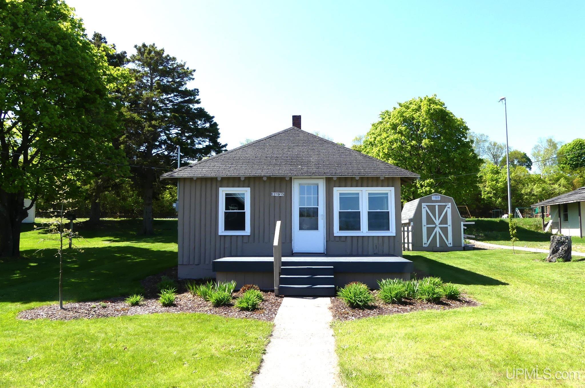 This quaint 1950's vertical log home is big on charm.  The lucky owners of this two bedroom, one bath home will enjoy peek-a-boo views of Grand Marais Bay and a coveted location right in the heart of town.  A large front deck overlooks the activity of town life and offers some great glimpses of Lake Superior.  The back fenced-in patio is perfect for pets or families with young children.  A barn style storage shed is on site for additional storage.  Recent updates include new windows, updated electrical panel with generator hook up, remodeled bathroom, septic system and gas oven/range.  Perennial beds and fruit trees complete the ideal picture of relaxation and home.  Take the next step toward your U.P. dream and schedule your showing, today!