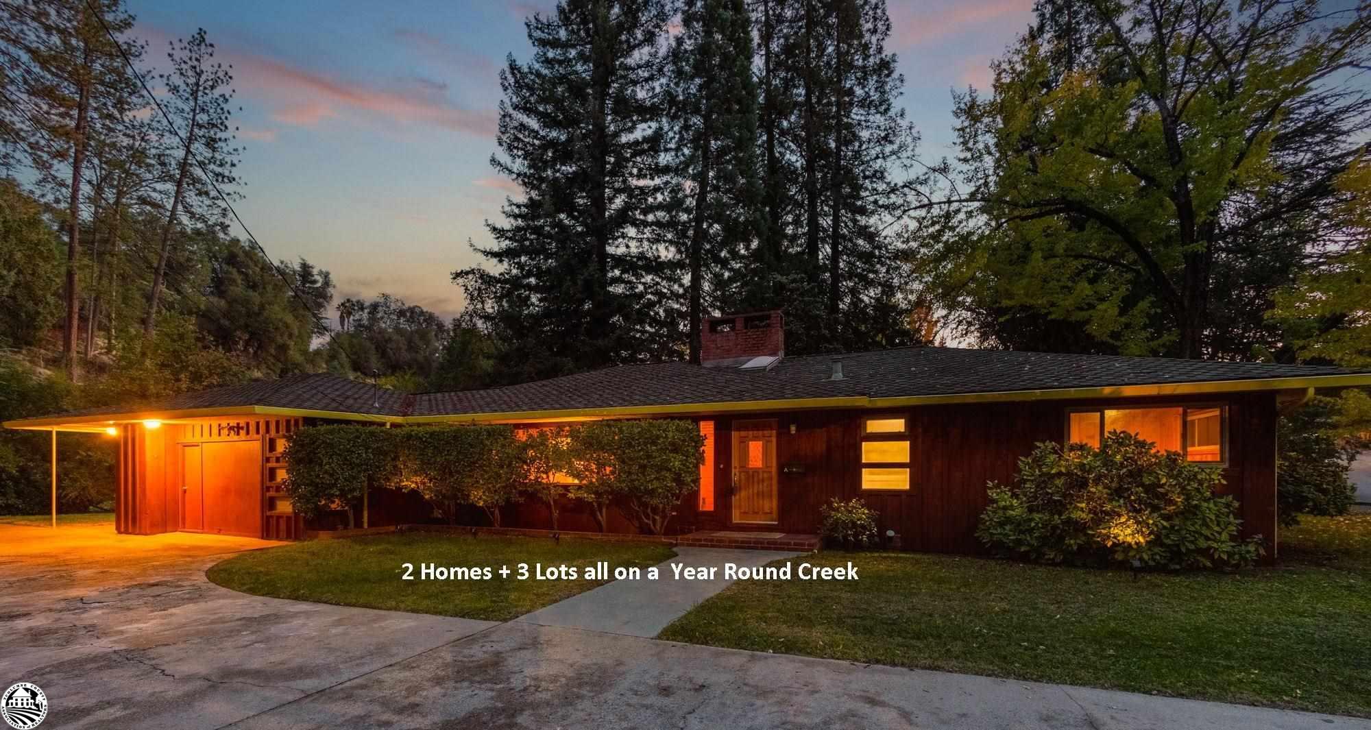 LOVELY MID CENTURY style home + IN LAW unit with a private, country feel near the heart of downtown Sonora. CREEKSIDE setting with over 500' of Woods Creek in your backyard with RIPARIAN RIGHTS included. 3 legal parcels make-up this enchanting setting with each parcel touching the creek. The home and in-unit occupy a 1/4 acre, while the other 2 legal parcels provide privacy and endless opportunities to garden and relax. The history of this "compound" is rich with stories of being a Christmas Tree farm, gold panning fun and year-round splashing in the creek. If you have a love for classic homes, this property is sure to capture your heart. The large roof overhang with soffits provides not only protection against the elements, but a place to relax and soak up the landscape. Floor to ceiling windows provide a scenic backdrop in the family room. Upper accent lights and a hand carved locally sourced mantle add just the right touch to create an inviting space. The brick accent around the fireplace can be enjoyed from both the family and living room. Warm, solid knotty cedar throughout the living room, with the iconic planter bed and skylight above at the main entry. The kitchen captures views to the creek and yard and offers a quaint breakfast nook. All your bedrooms and a full bathroom are down the hall, with each bedroom having unique features. Built-in's, pristine wood paneling and spacious closets enhance these rooms. The hall bathroom offers tile flooring, a single vanity sink with accent lighting, powder desk and soaking tub. The second bathroom is near the garage offering a tile stall shower with green trim tile accents and glass block walls. As with all older homes you can find a basement beneath, providing a great space for canned goods and storage. The stand alone IN-LAW UNIT offers a 1 bedroom, 1 bathroom space with a full kitchen and year round sounds of the creek.  As you cross the bridge you will feel as though you are out in the countryside with all the established fruit trees and 2,000sqft garden just waiting to be revived. This home has provided many years of enjoyment to the owners and their family members who feel the easy walk to town is just another perk of residing here. Sonora CA is one of the oldest cities in California providing a great basecamp for visitors to explore Yosemite National Park, Pinecrest Lake, Eastern Sierras and as always excellent shopping and dining.