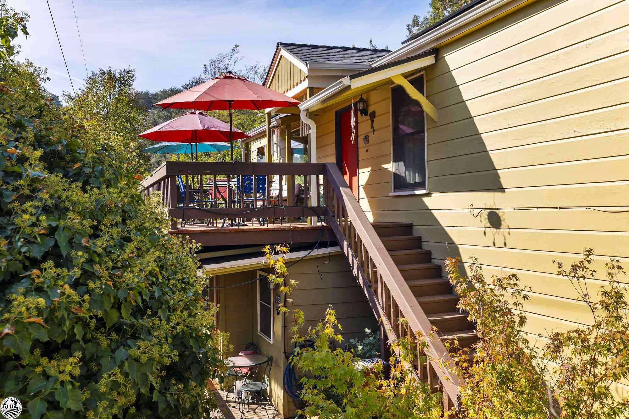 Open House Sunday 1-4pm!!! Artistic and Joyful Vibe in Downtown Sonora. Tucked up off the street, this colorful cottage is a hidden gem. As you walk up on the front deck the cozy view of the trees, the multiple seating areas and the colorful front door set the stage perfectly. Inside, the warmth of the wood floors and touches of wood paneling are a perfect complement to the rooms’ rich paint colors. The main living area opens to a small sitting area on one side, perfect for a reading nook or home office, and on the other side, it opens to the dining room. There is a freestanding propane stove and a large window looking out to the deck that brings in the natural light. The dining room’s high pine ceiling and multiple wood framed windows give the space a real cozy and cottage-like feel. From there, you enter the kitchen which is colorful, vibrant, and pure joy. The white quartz counter tops and stainless-steel appliances are a nice contrast to the vibrant colors and the terracotta-colored tile floor keeps it all very grounded. Off the kitchen is a laundry room/pantry that is very spacious and functional. There are 2 nice-sized bedrooms and a bathroom on the main floor. The downstairs is accessed via stairs off the living room’s sitting area as well as via the lower front yard exterior door. There are 2 sitting areas, a small kitchenette, a sleeping area, and a bathroom with a shower. It can be closed off from the main living area and used as a separate living space, or the door can be opened and used as an extension of the main space. Currently, the owners rent it out for $1,300 per month. What a great way to supplement the mortgage if you don’t need the extra space! In addition to the space in the home, there are also a detached office and a detached artist studio on the property. The backyard is magical with charming rock walls and stairs meandering through the yard’s multiple sitting areas and well-established foliage. It is peaceful, private, and absolutely dreamy. There is also a roof top garden/sitting area over the detached garage. The property goes from street to street and there is an off-street parking space on Oakside. Located on Myers Hill, you cannot beat the location and its proximity to the farmer’s market, shops, and restaurants. Check out the 3D tour to appreciate all this home has to offer.